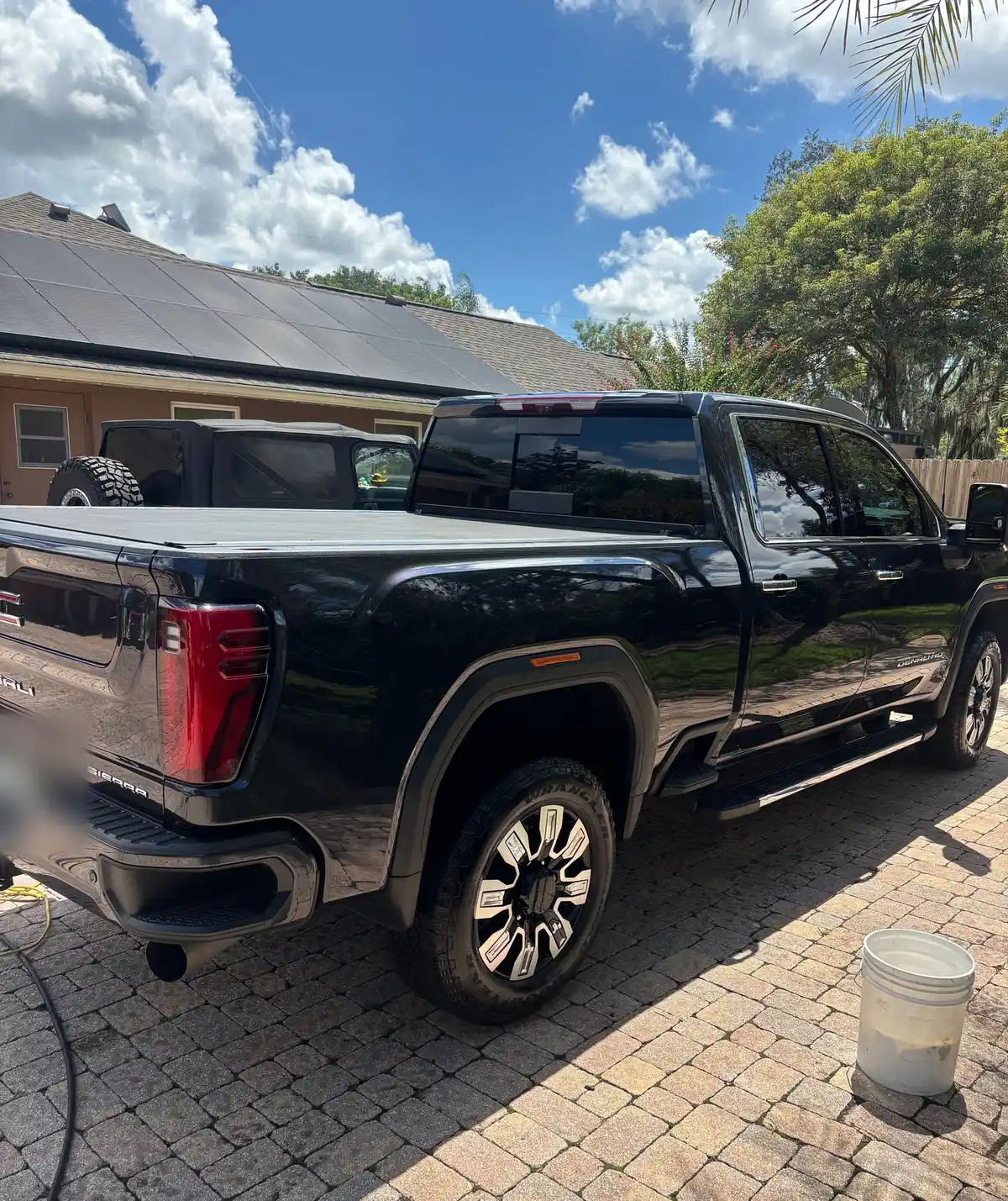 Rear three-quarter view of the black GMC Sierra Denali after an on-site detail