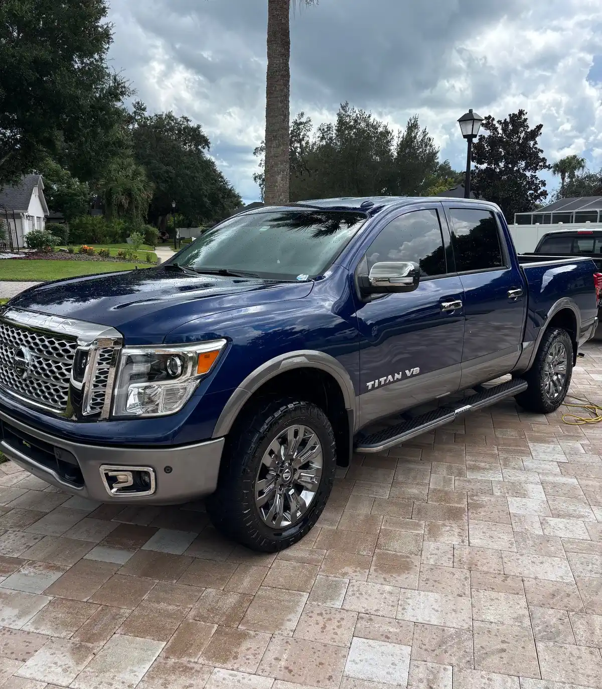 Blue Nissan Titan pickup after an on-site detail on a paver driveway