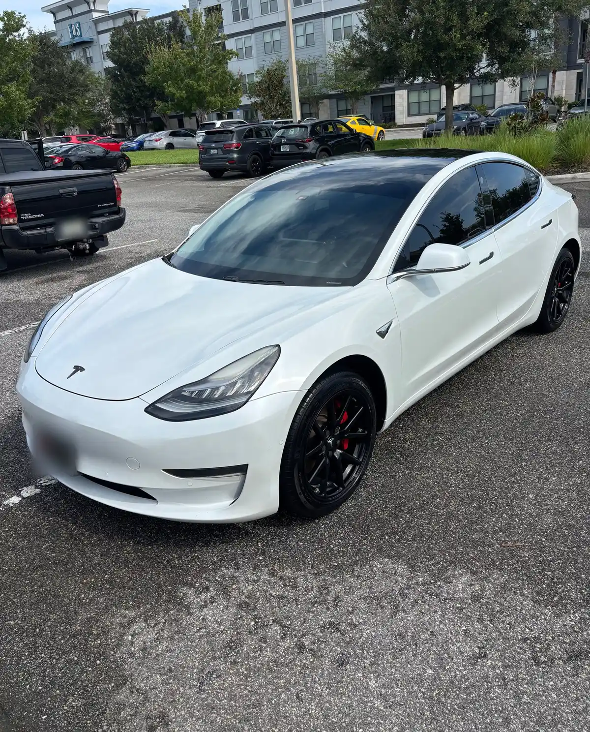 White Tesla Model 3 after a detail, parked in an apartment complex lot